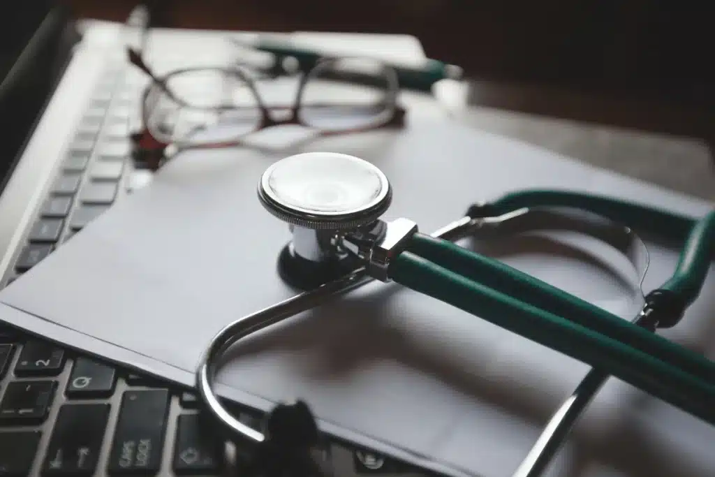 Stethescope, paperwork and glasses on top of a keyboard