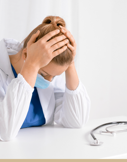 Florida doctor sitting down, wearing a mask and holding her head, distressed