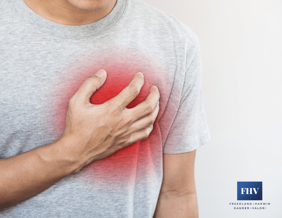 A person clutches his chest in pain, indicating discomfort or possible heart trouble.