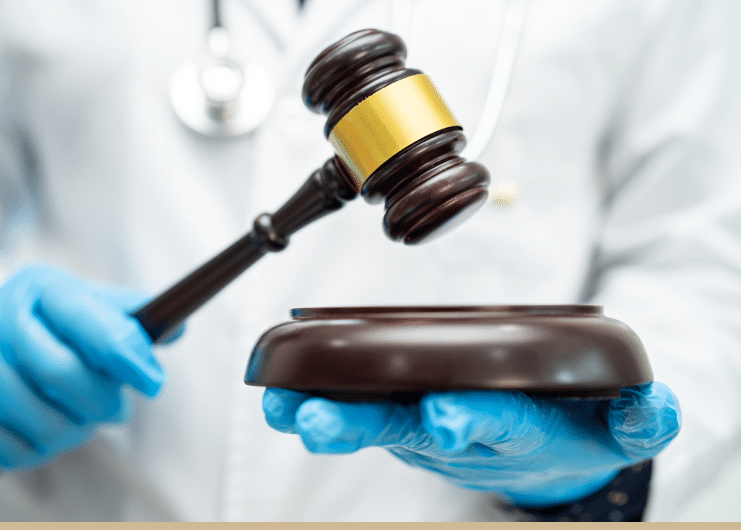 Doctor with blue sterile gloves on holding a gavel